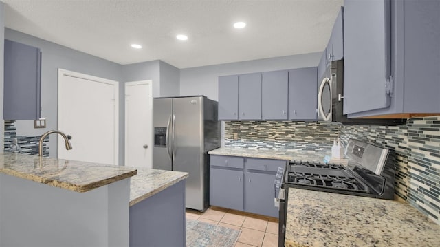 12307 Emery Oaks Rd, Austin, TX 78758 - kitchen featuring appliances with stainless steel finishes, gray cabinetry, a peninsula, decorative backsplash, and light tile patterned floors