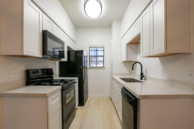 203 E 31st St Unit 206, Austin, TX 78705 - kitchen with black appliances, light countertops, a textured ceiling, light wood finished floors, and white cabinets