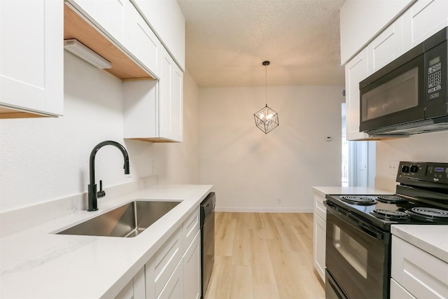 203 E 31st St Unit 206, Austin, TX 78705 - kitchen with black appliances, light wood-style flooring, white cabinetry, light countertops, and decorative light fixtures