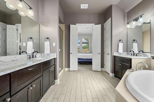21506 Greylag Dr, Pflugerville, TX 78660 - bathroom with a shower stall, two vanities, a garden tub, connected bathroom, and wood finished floors