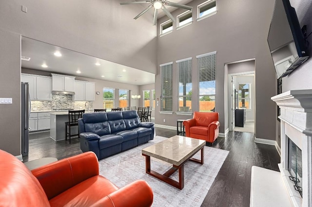 21506 Greylag Dr, Pflugerville, TX 78660 - living area with a ceiling fan, a fireplace, dark wood-style flooring, a towering ceiling, and recessed lighting