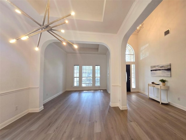 10303 Spicewood Pkwy, Austin, TX 78750 - unfurnished living room with arched walkways, healthy amount of natural light, wood finished floors, a raised ceiling, and ornamental molding
