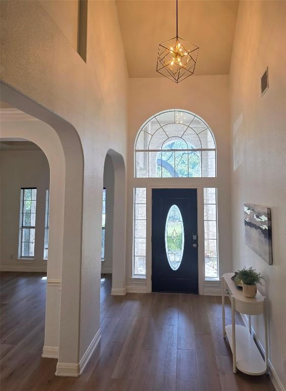 10303 Spicewood Pkwy, Austin, TX 78750 - entrance foyer featuring arched walkways, high vaulted ceiling, wood-type flooring, and a chandelier