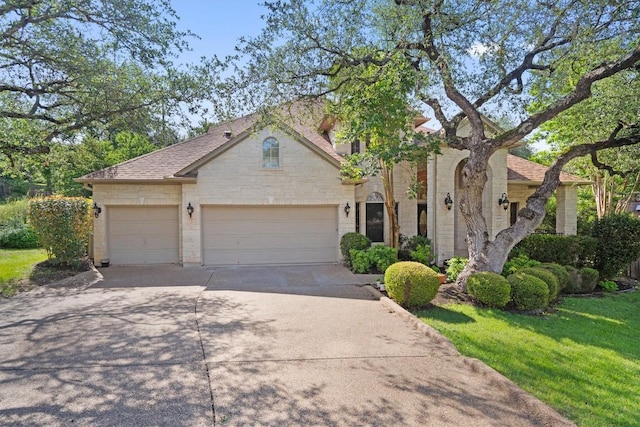10303 Spicewood Pkwy, Austin, TX 78750 - view of front of house featuring concrete driveway, an attached garage, stone siding, a shingled roof, and a front lawn