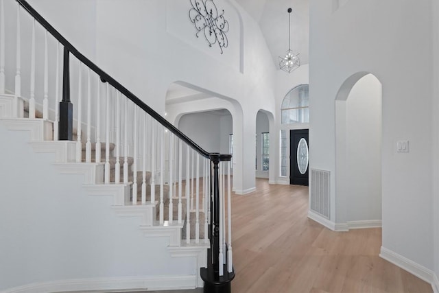 10303 Spicewood Pkwy, Austin, TX 78750 - entryway with arched walkways, a high ceiling, stairway, and light wood-type flooring