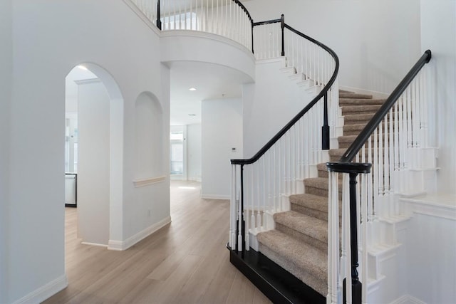 10303 Spicewood Pkwy, Austin, TX 78750 - stairs with a towering ceiling, wood finished floors, and arched walkways
