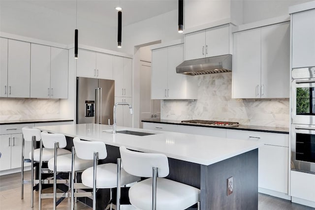 6702 Adeline Way Unit 34, Austin, TX 78746 - kitchen featuring appliances with stainless steel finishes, under cabinet range hood, a breakfast bar area, and tasteful backsplash