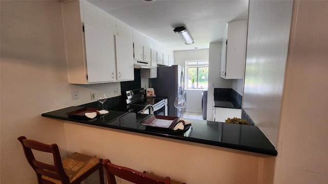 7122 Wood Hollow Dr Unit 41, Austin, TX 78731 - kitchen featuring appliances with stainless steel finishes, under cabinet range hood, white cabinets, a peninsula, and dark countertops