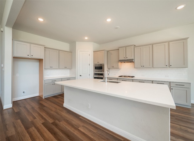 2320 Lucky Ln, Leander, TX 78641 - kitchen with stainless steel appliances, tasteful backsplash, an island with sink, dark wood finished floors, and under cabinet range hood