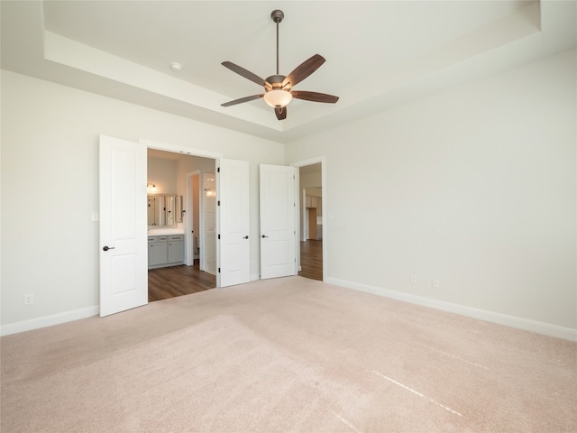 2320 Lucky Ln, Leander, TX 78641 - unfurnished bedroom featuring carpet floors, ensuite bathroom, ceiling fan, and a tray ceiling
