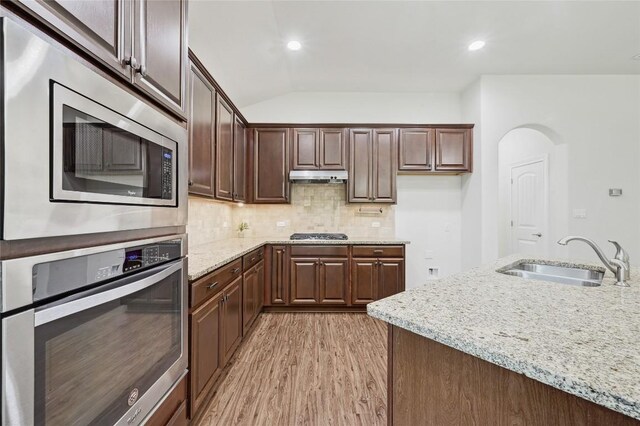 2232 Skippy Cv, Leander, TX 78641 - kitchen with stainless steel appliances, light wood-style flooring, under cabinet range hood, light stone counters, and backsplash