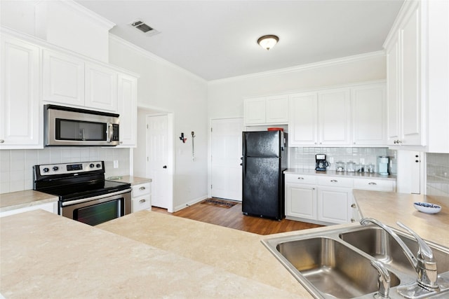 2806 Truman Cv, Lago Vista, TX 78645 - kitchen featuring appliances with stainless steel finishes, white cabinets, light countertops, crown molding, and tasteful backsplash