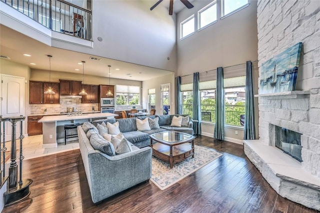 110 Waverly Spire Ct, Austin, TX 78738 - living room featuring ceiling fan, a towering ceiling, a fireplace, and hardwood / wood-style flooring