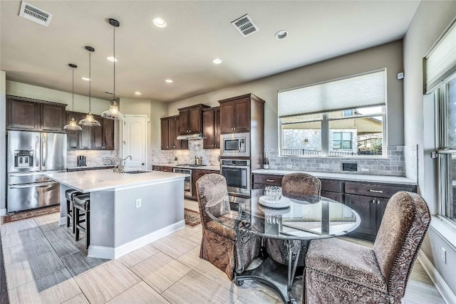 110 Waverly Spire Ct, Austin, TX 78738 - kitchen with stainless steel appliances, dark brown cabinetry, light countertops, decorative backsplash, and recessed lighting