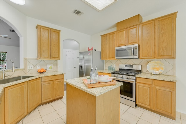 7008 Wandering Oak Rd, Austin, TX 78749 - kitchen featuring appliances with stainless steel finishes, arched walkways, light stone counters, and decorative backsplash