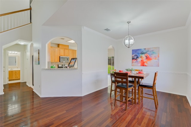7008 Wandering Oak Rd, Austin, TX 78749 - dining area featuring dark wood-style floors, arched walkways, crown molding, and a chandelier