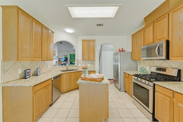 7008 Wandering Oak Rd, Austin, TX 78749 - kitchen featuring appliances with stainless steel finishes, decorative backsplash, arched walkways, and a kitchen island