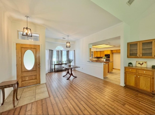 224 Crooked Hollow Dr, Elgin, TX 78621 - entrance foyer with light wood finished floors, a chandelier, and crown molding