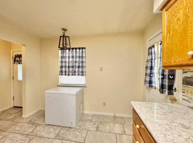 224 Crooked Hollow Dr, Elgin, TX 78621 - kitchen featuring fridge, brown cabinets, decorative light fixtures, and light stone counters