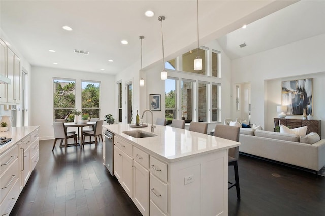 4108 Logan Ridge Dr, Cedar Park, TX 78613 - kitchen with a breakfast bar, dark wood-type flooring, stainless steel dishwasher, white cabinetry, and a kitchen island with sink