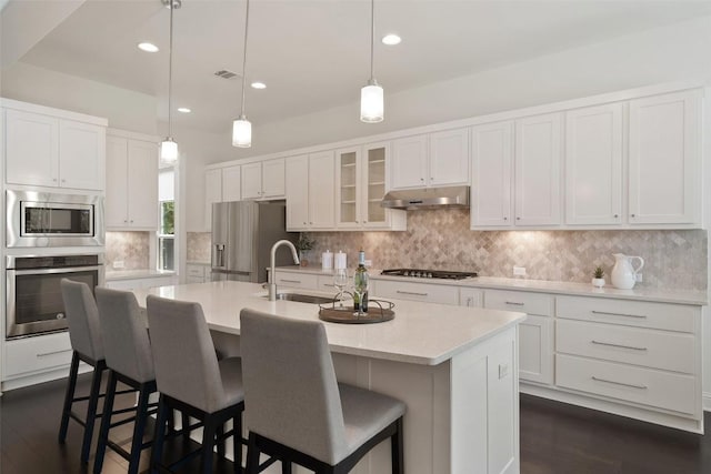 4108 Logan Ridge Dr, Cedar Park, TX 78613 - kitchen featuring stainless steel appliances, under cabinet range hood, light countertops, white cabinetry, and backsplash