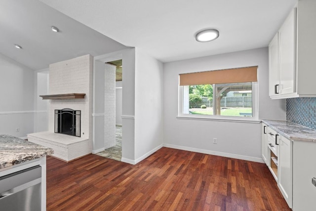 501 Meadowbrook Dr, Georgetown, TX 78628 - kitchen featuring white cabinetry, dark wood-style flooring, light stone counters, a fireplace, and backsplash
