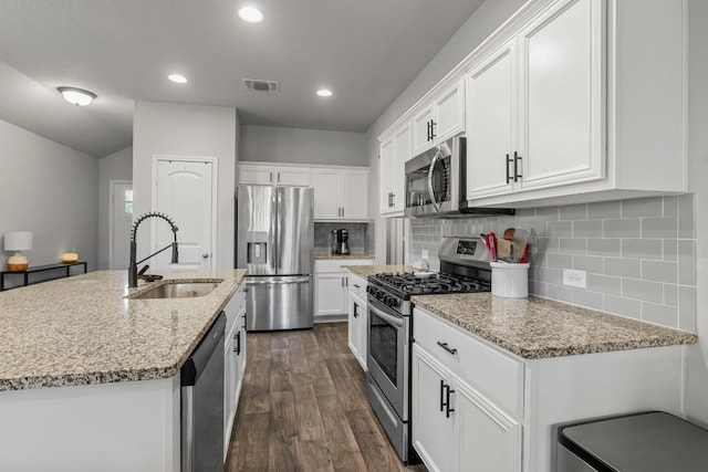 13911 Macquarie Dr, Pflugerville, TX 78660 - kitchen with appliances with stainless steel finishes, dark wood-type flooring, white cabinetry, decorative backsplash, and recessed lighting