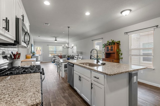 13911 Macquarie Dr, Pflugerville, TX 78660 - kitchen with stainless steel appliances, open floor plan, white cabinets, dark wood finished floors, and recessed lighting