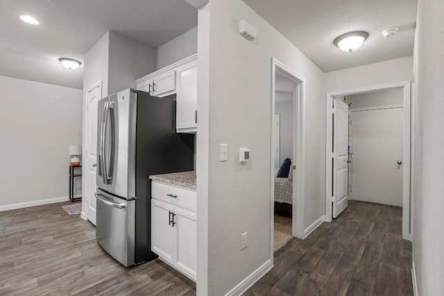 13911 Macquarie Dr, Pflugerville, TX 78660 - kitchen with freestanding refrigerator, dark wood-style floors, white cabinetry, and light stone counters