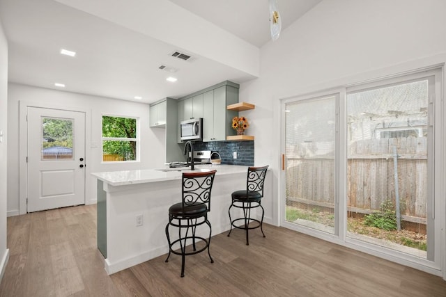 7913 W Gate Blvd Unit A, Austin, TX 78745 - kitchen featuring stainless steel microwave, a peninsula, light countertops, open shelves, and light wood finished floors