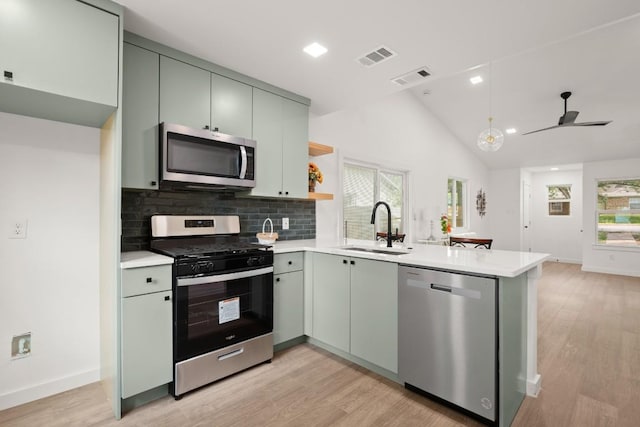 7913 W Gate Blvd Unit A, Austin, TX 78745 - kitchen featuring stainless steel appliances, a peninsula, light wood finished floors, tasteful backsplash, and light countertops