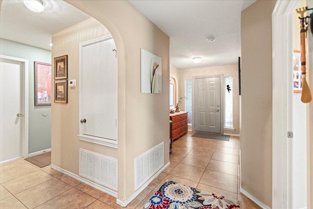 foyer entrance featuring light tile patterned flooring and arched walkways