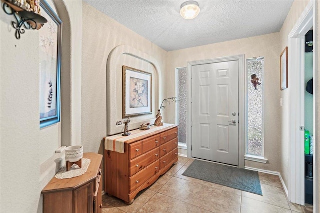 foyer with a textured ceiling and light tile patterned floors