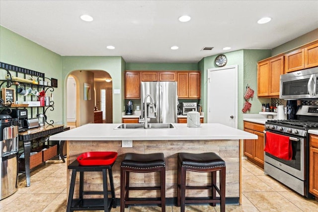 kitchen with stainless steel appliances, recessed lighting, a kitchen island with sink, light countertops, and light tile patterned floors