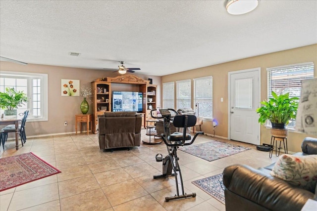 living room featuring healthy amount of natural light, a ceiling fan, light tile patterned floors, and a textured ceiling