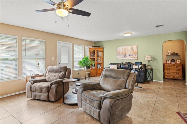 living area with a ceiling fan, light tile patterned flooring, and a textured ceiling