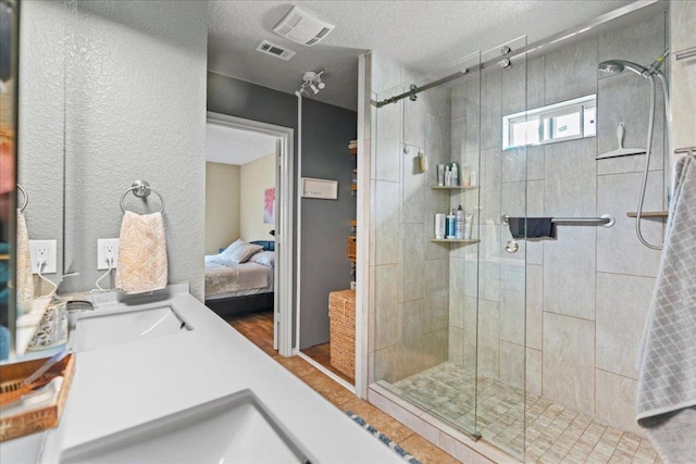 ensuite bathroom with a stall shower, vanity, wood finished floors, and a textured ceiling