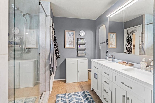 full bath featuring double vanity, a stall shower, and tile patterned flooring