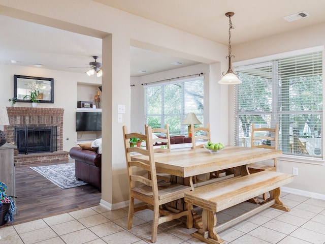 2407 Silver Spur Ln, Leander, TX 78641 - dining room featuring light tile patterned floors, ceiling fan, and a brick fireplace