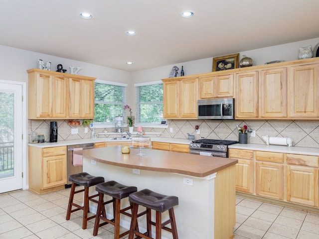 2407 Silver Spur Ln, Leander, TX 78641 - kitchen featuring stainless steel appliances, light brown cabinets, light tile patterned flooring, backsplash, and recessed lighting