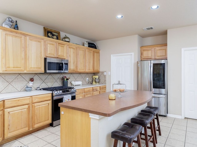 2407 Silver Spur Ln, Leander, TX 78641 - kitchen featuring appliances with stainless steel finishes, light tile patterned flooring, tasteful backsplash, a breakfast bar, and recessed lighting