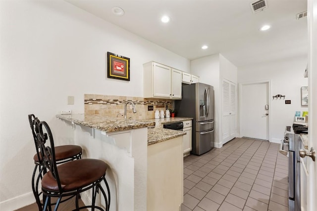8600 Cima Oak Ln Unit A15, Austin, TX 78759 - kitchen with stainless steel appliances, a peninsula, a breakfast bar area, light tile patterned flooring, and tasteful backsplash