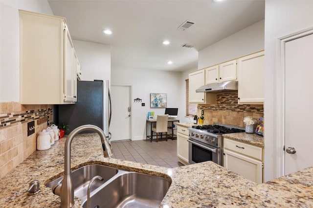 8600 Cima Oak Ln Unit A15, Austin, TX 78759 - kitchen with appliances with stainless steel finishes, under cabinet range hood, tasteful backsplash, light stone counters, and recessed lighting