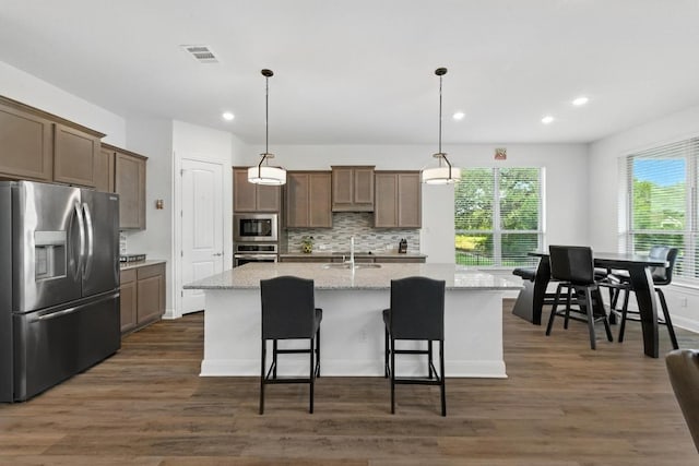 216 Tovas Secret Cv, Georgetown, TX 78628 - kitchen with appliances with stainless steel finishes, an island with sink, recessed lighting, dark wood-style floors, and tasteful backsplash