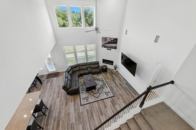 216 Tovas Secret Cv, Georgetown, TX 78628 - living area featuring a high ceiling, a ceiling fan, wood finished floors, and a glass covered fireplace