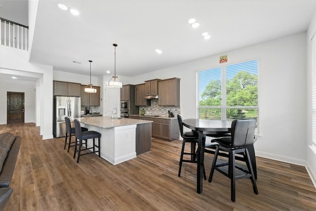 216 Tovas Secret Cv, Georgetown, TX 78628 - kitchen with stainless steel appliances, dark wood-style floors, an island with sink, recessed lighting, and decorative backsplash