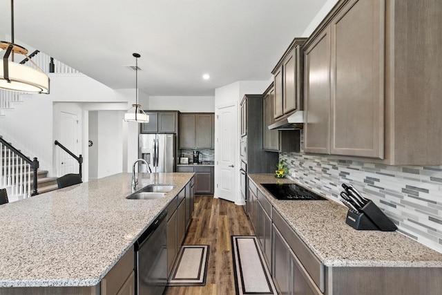 216 Tovas Secret Cv, Georgetown, TX 78628 - kitchen featuring dark wood-type flooring, appliances with stainless steel finishes, decorative backsplash, light stone countertops, and a center island with sink