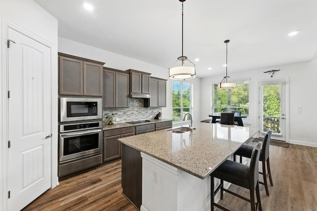 216 Tovas Secret Cv, Georgetown, TX 78628 - kitchen featuring recessed lighting, stainless steel appliances, light stone counters, a center island with sink, and dark wood-style floors