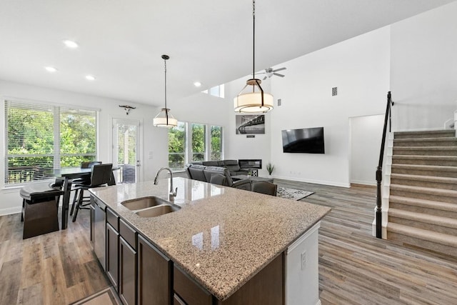 216 Tovas Secret Cv, Georgetown, TX 78628 - kitchen with light wood-type flooring, recessed lighting, decorative light fixtures, a kitchen island with sink, and light stone counters