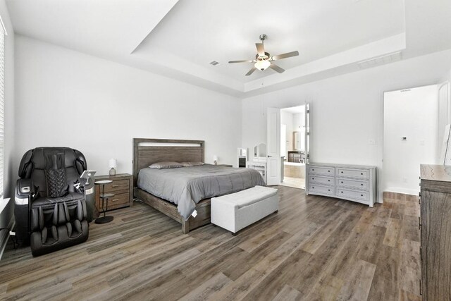 216 Tovas Secret Cv, Georgetown, TX 78628 - bedroom featuring a tray ceiling, wood finished floors, connected bathroom, and a ceiling fan